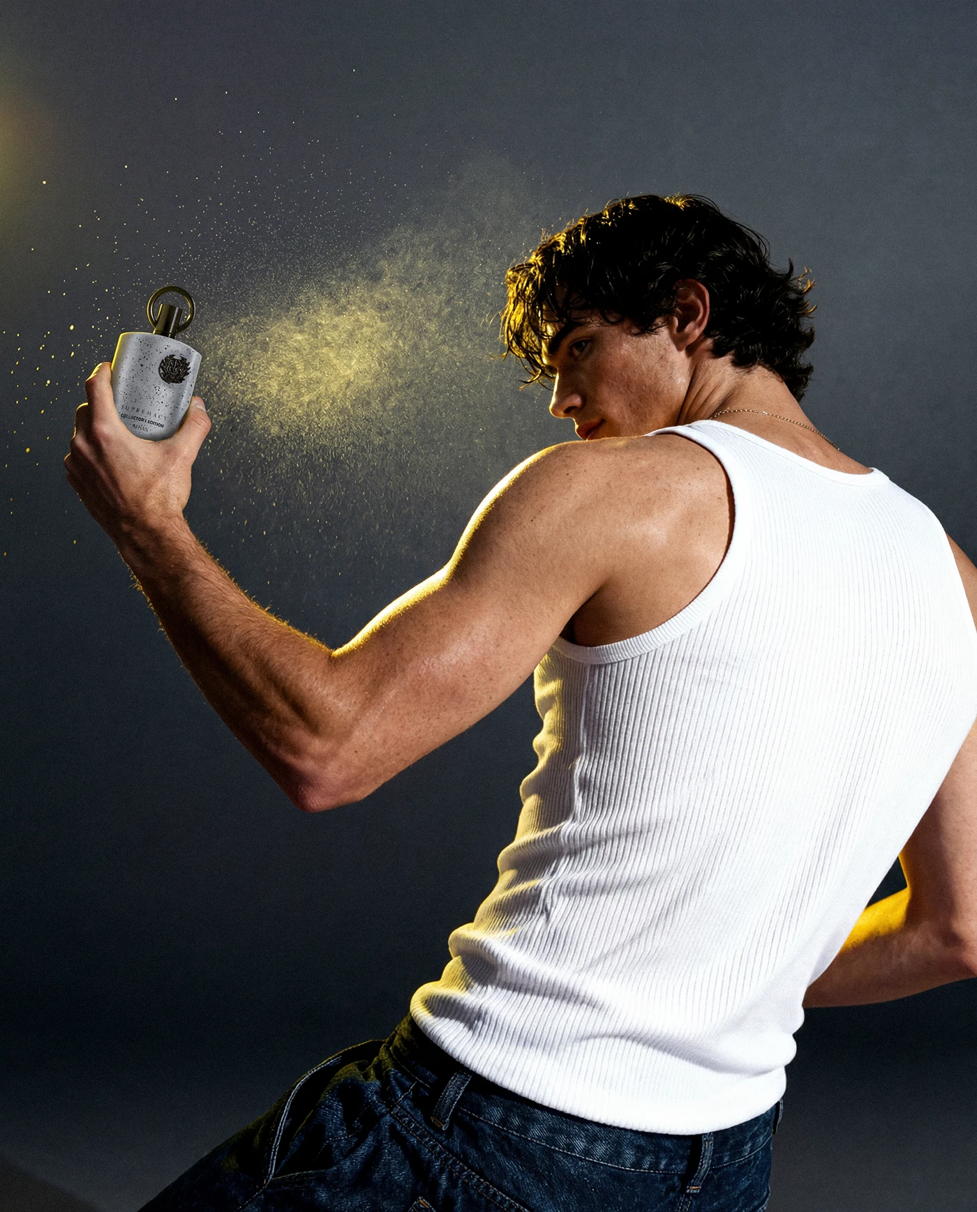 Model spraying the Supremacy perfume under a hard studio light