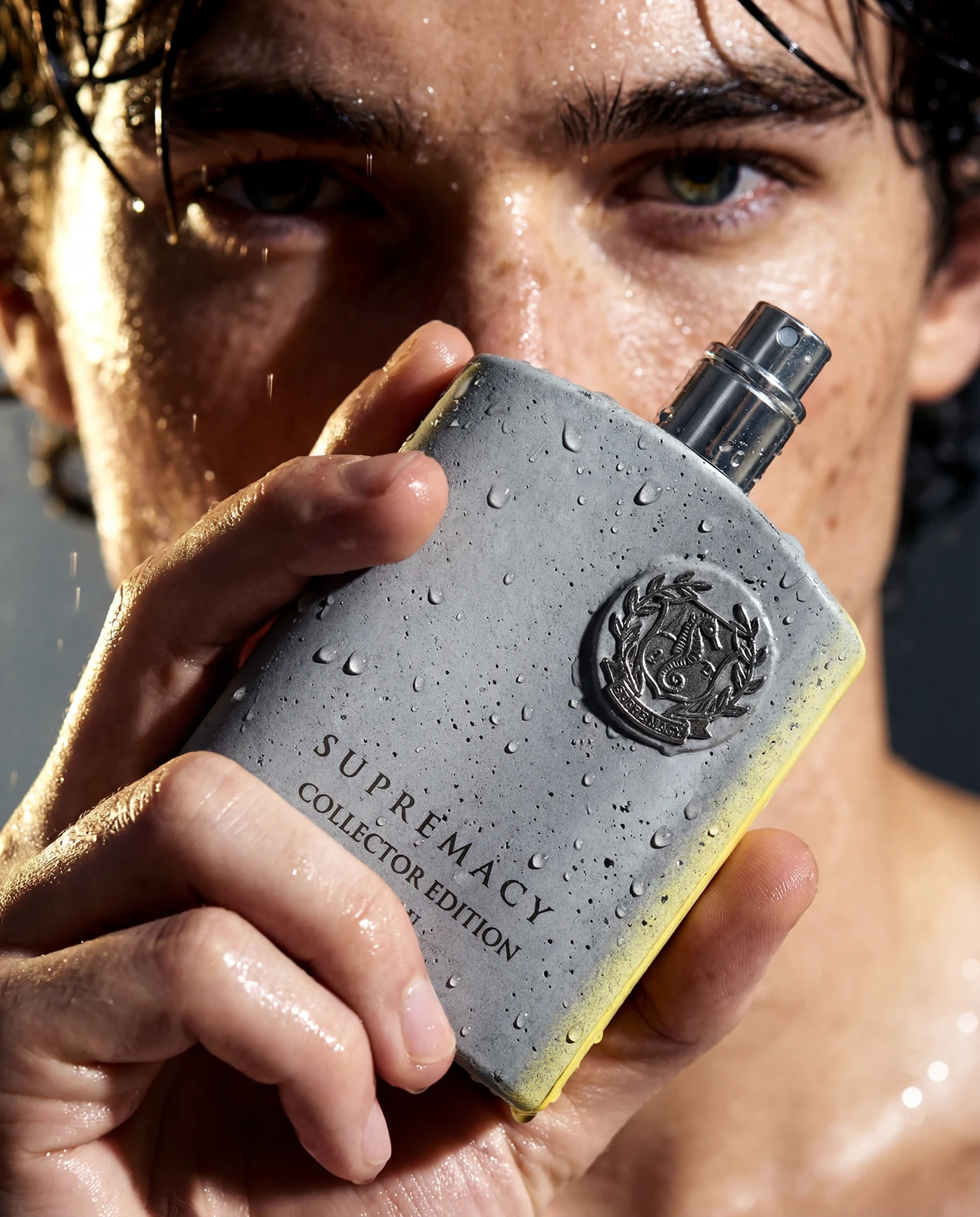 Close-up of a hand holding the Supremacy Collector's Edition bottle near the model's face